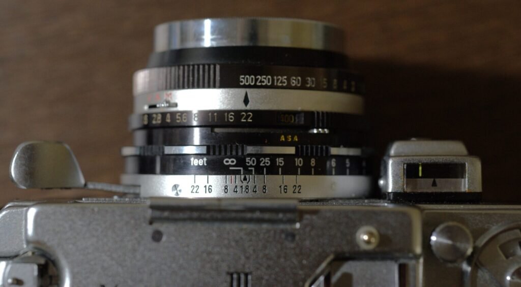 Các điều khiển chủ yếu trên máy (từ trái qua phải): cần gạt film, ống lens chỉnh khẩu độ, mà trập, đồng hồ đo kim. Nút chụp ở góc dưới bên phải.